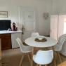 Kitchen seating area with round table and four white chairs on a carpet.