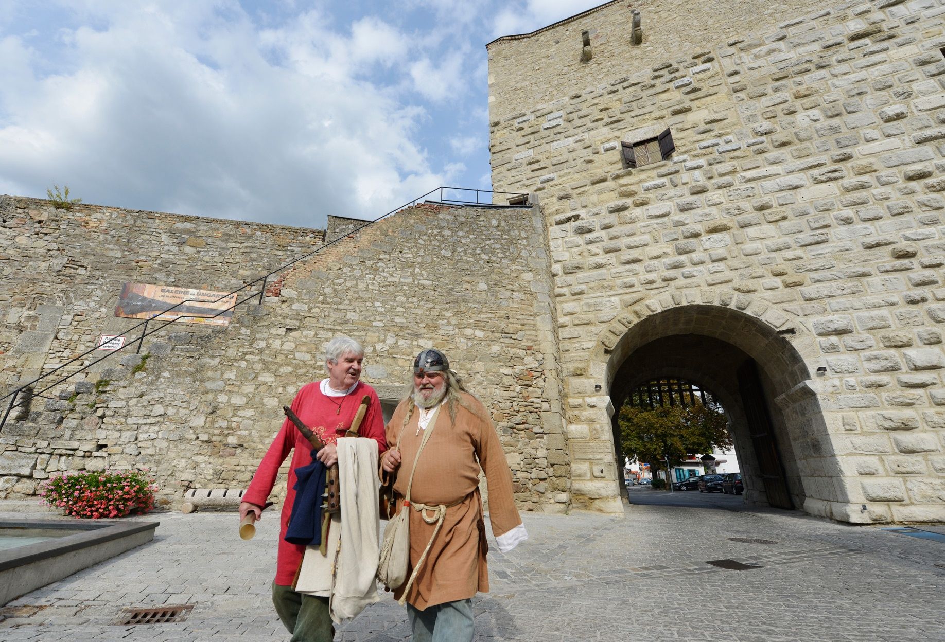 Zwei Männer in mittelalterlicher Kleidung vor einer alten Steinmauer in Hainburg an der Donau.
