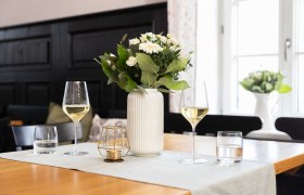 Tisch mit zwei Weingläsern, Vase und Kerze