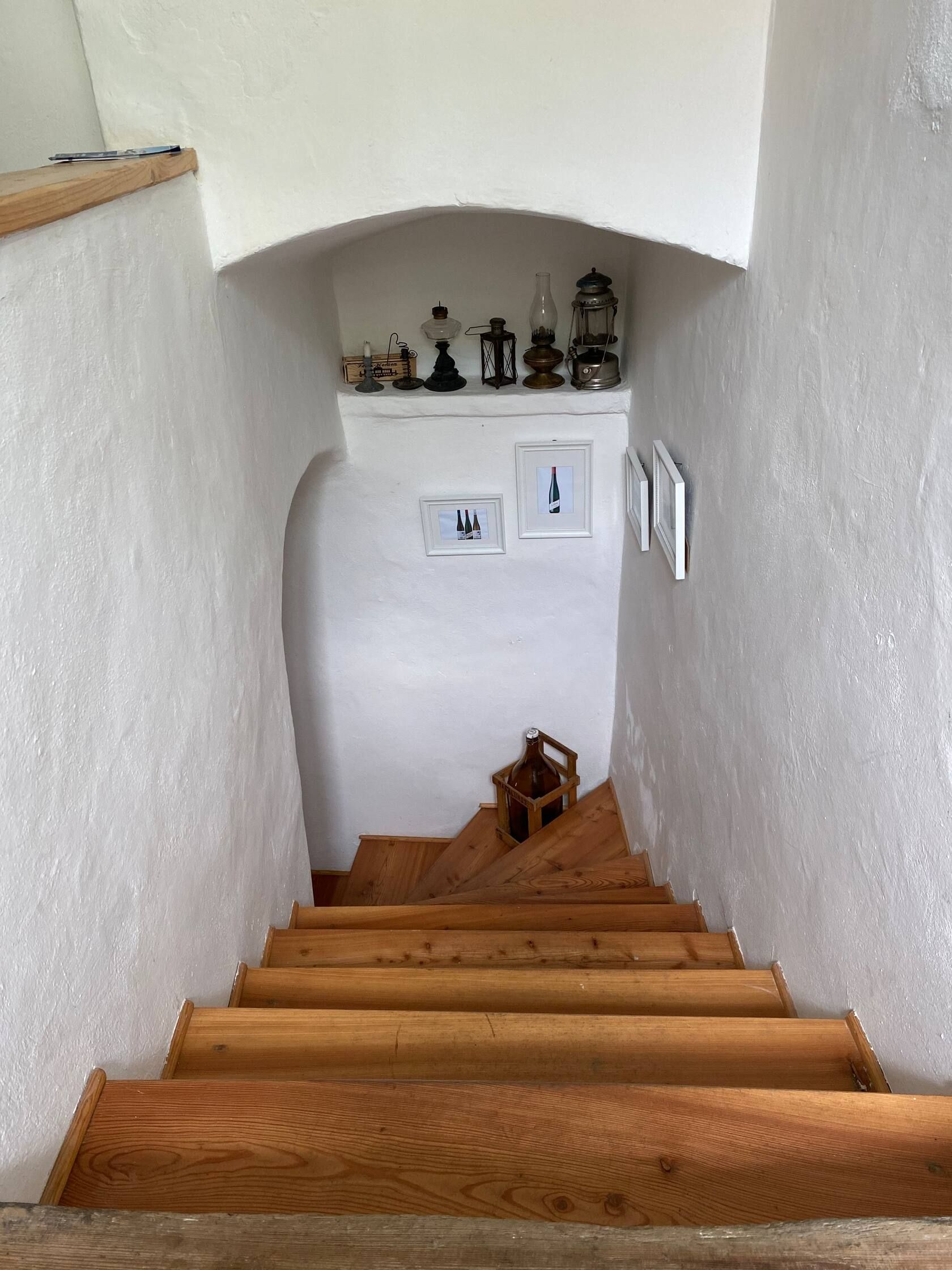 Holztreppe in einem weißen Treppenhaus mit Dekorationen und Bildern an den Wänden.