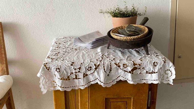 A small wooden table with a lace ceiling, plants and a framed picture on the wall.