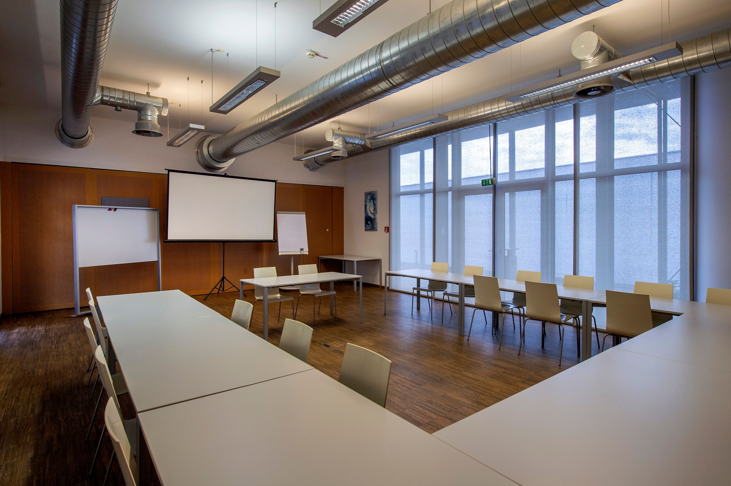 Seminarraum mit Tischen, Stühlen und Projektionsleinwand.