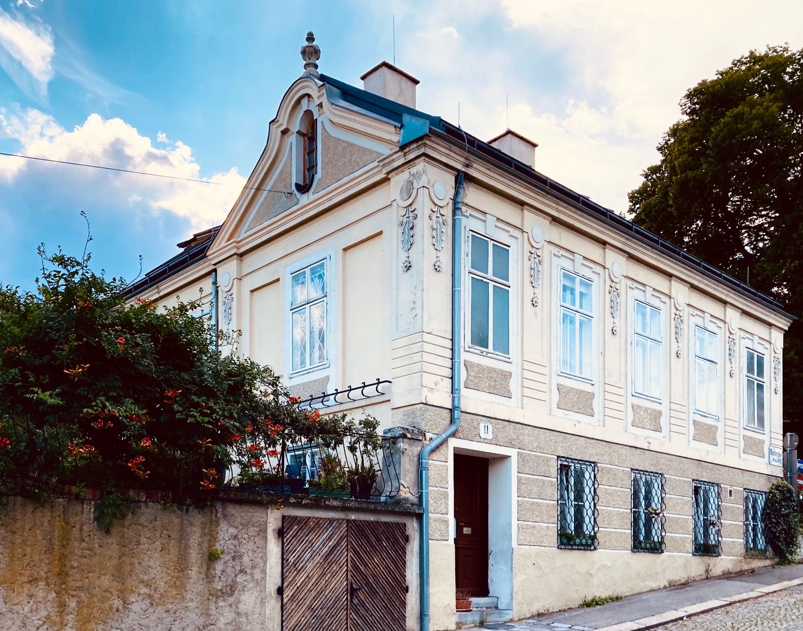 Außenansicht einer historischen Villa mit verzierten Fenstern und einem Giebel.