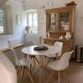 Dining area with round table, four white chairs, wooden cupboard and decoration in a bright room.