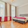 Bright hotel room with double bed, desk and chair.