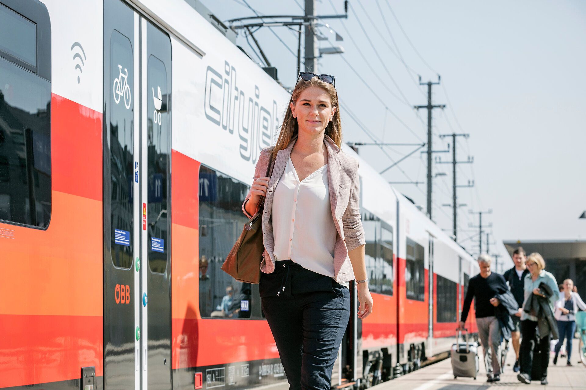 Die Sonne strahlt über den Bahnhof, während Reisende mit Vorfreude auf ihre Zugfahrt in die Berge schlendern. Die frische Luft und das sanfte Rauschen der Züge schaffen eine einladende Atmosphäre für alle, die das Abenteuer in der Natur suchen.