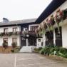 A traditional country inn with balconies decorated with flowers and an entrance with stairs.