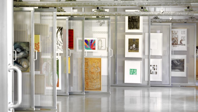 Interior view of an art library with works of art on movable shelves.