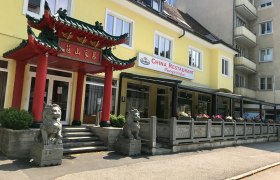 Außenansicht eines chinesischen Restaurants mit traditionellem Tor und Löwenstatuen.