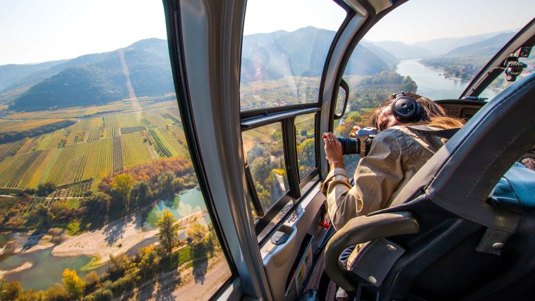 View from a helicopter of a landscape with a river and fields.