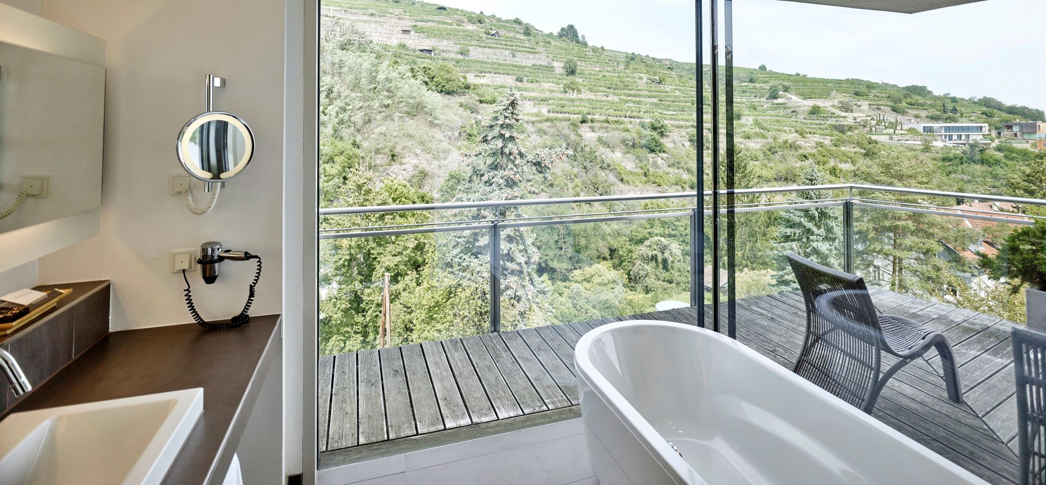 Badezimmer mit freistehender Badewanne und Blick auf Weinberge.