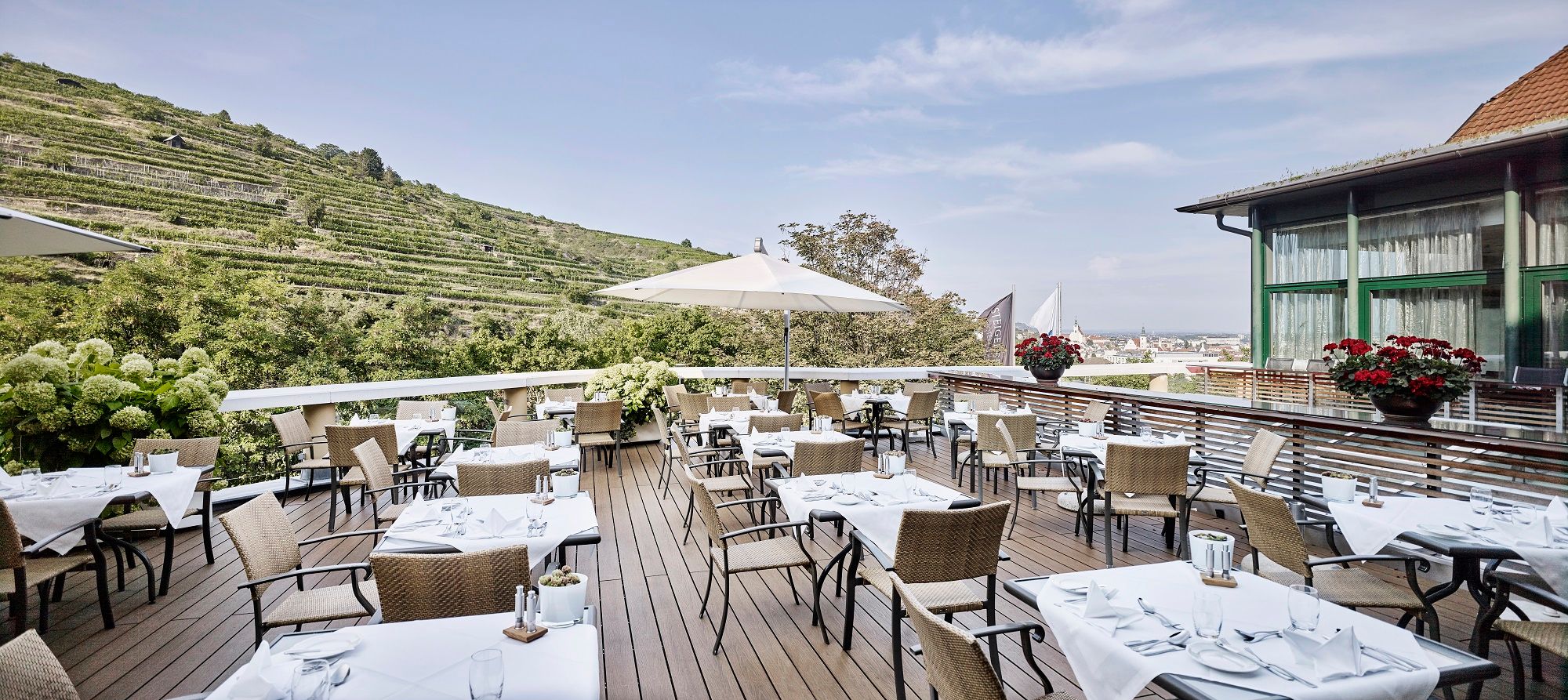 Terrasse des Steigenberger Hotels mit gedeckten Tischen und Blick auf Weinberge.