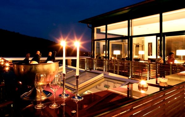 Abendliche Restaurantterrasse mit Kerzenlicht und Weingläsern.