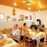 People have breakfast in a cozy room with wooden furniture and decorations on the wall.