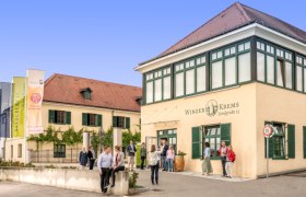 Gebäude von Winzer Krems mit Menschen davor.