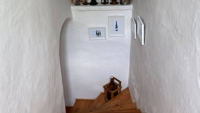 Wooden staircase in a white stairwell with decorations and pictures on the walls.