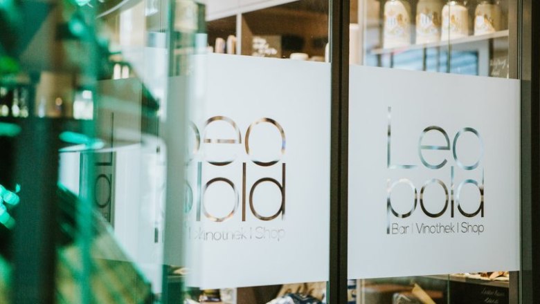 Entrance to the vinotheque with the lettering 'Leopold Bar Vinothek Shop' on the glass door.