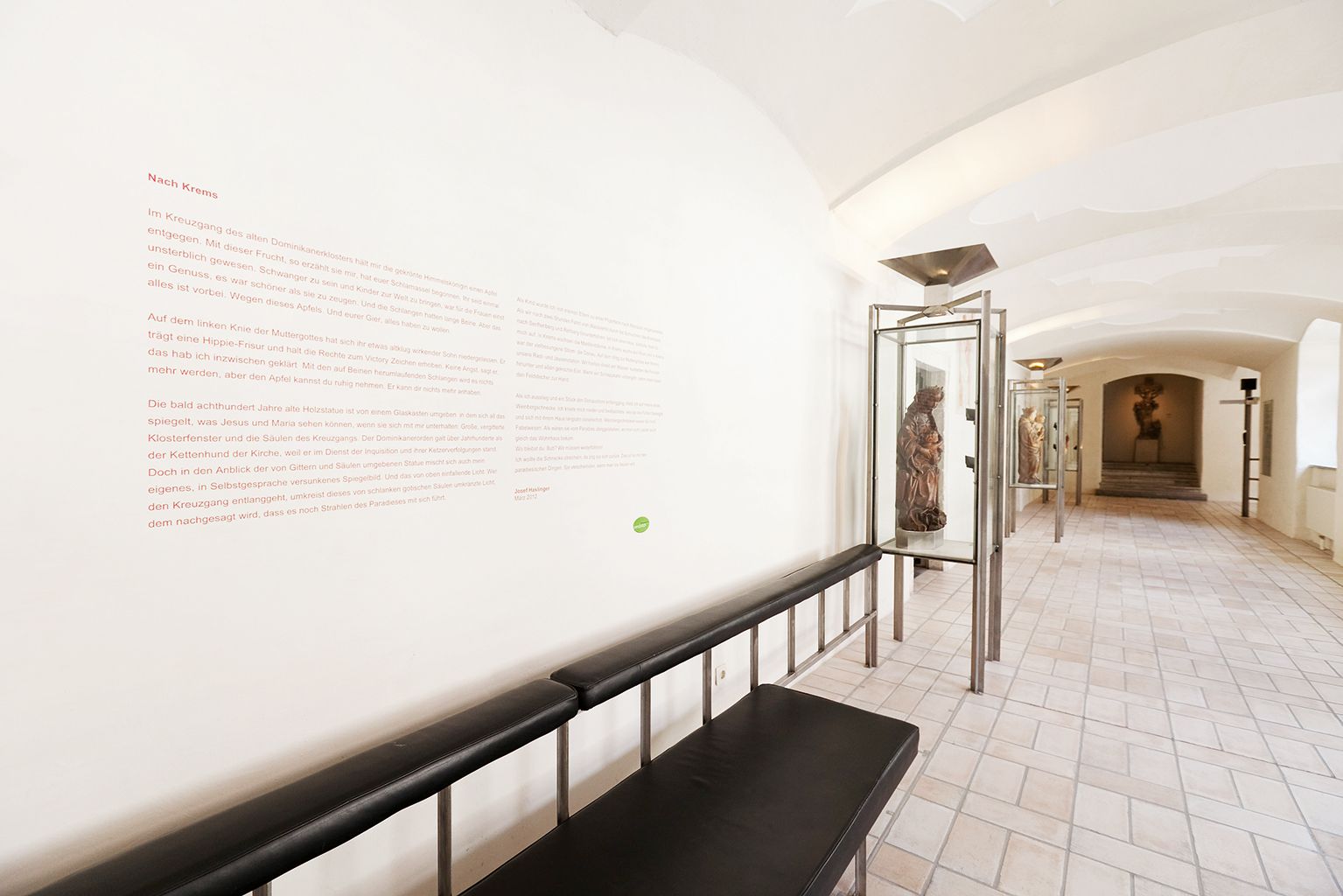 Ein Museumsflur mit Skulpturen in Glasvitrinen und einem Text an der Wand.