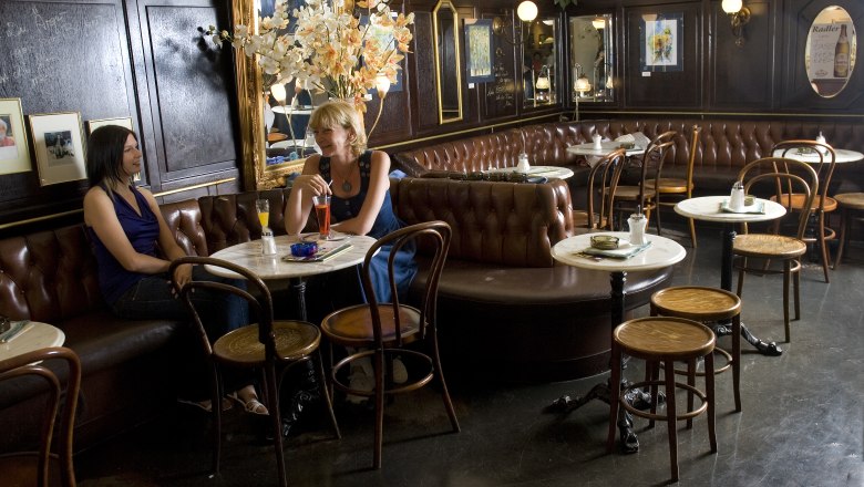 Innenansicht eines traditionellen Cafés mit zwei Frauen, die an einem Tisch sitzen.