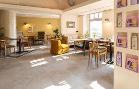 Innenansicht eines gemütlichen Cafés mit Holzmöbeln und Pflanzen.