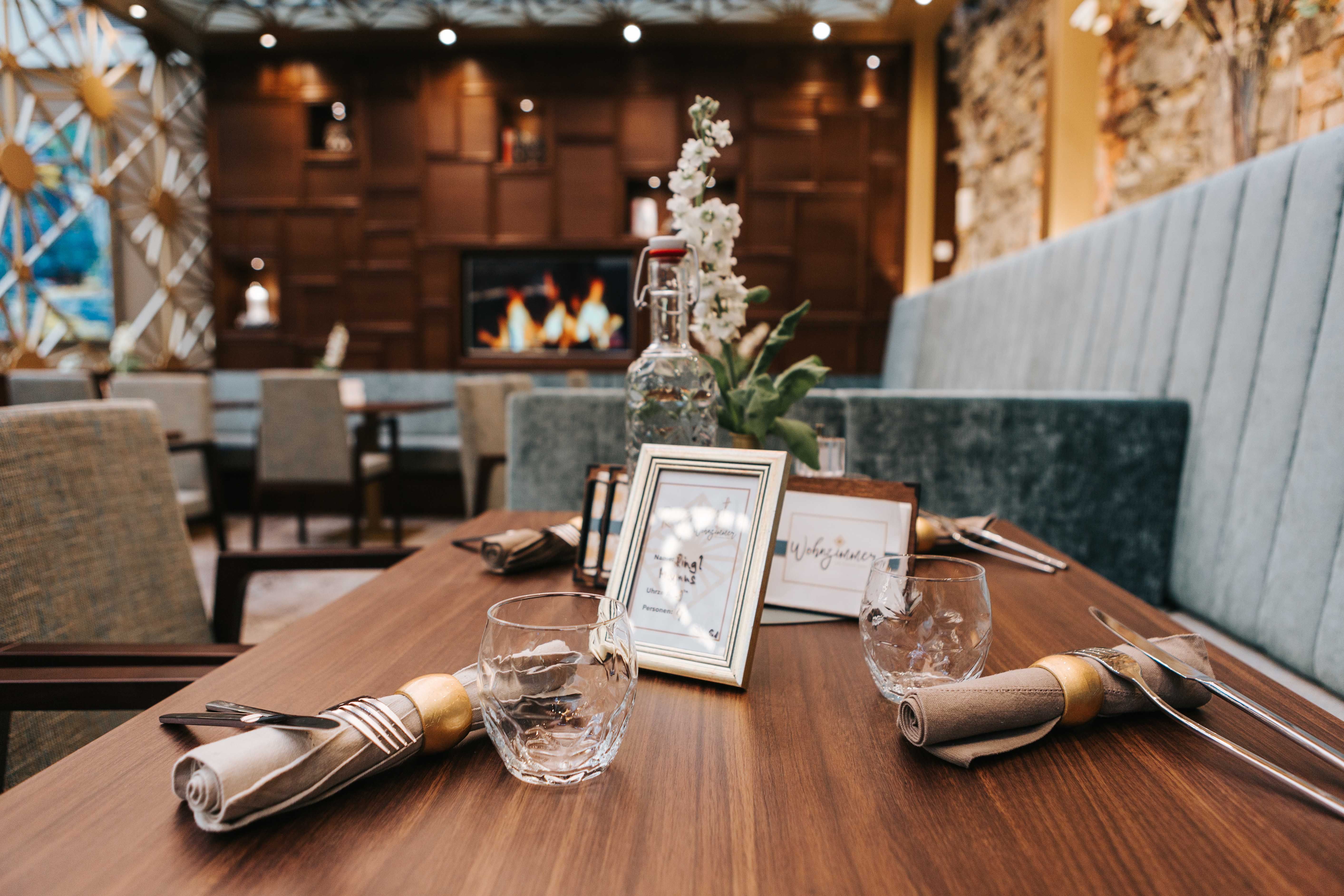 Ein stilvoll gedeckter Tisch in einem Café mit Holzdekor und Kamin im Hintergrund.
