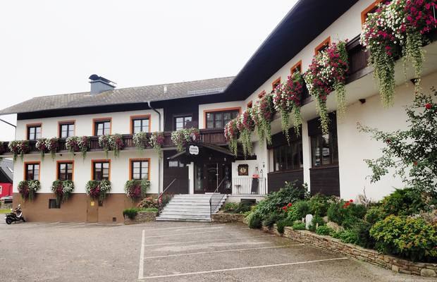 A traditional country inn with balconies decorated with flowers and an entrance with stairs.