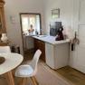 Kitchen area with small table, chair, sink and coffee machine. Windows with decoration and bright walls.