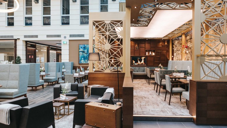 Innenansicht eines modernen Caf&eacute;s mit gem&uuml;tlichen Sitzbereichen, Kamin und stilvoller Dekoration.