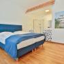 Hotel room with blue bed, wooden floor and open shower.