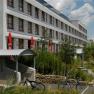 Modern building with several floors, surrounded by green landscape and bicycles in the foreground.