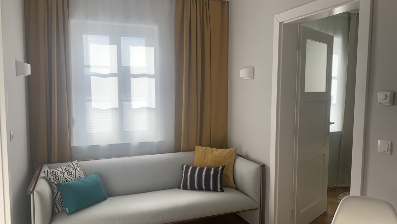 Cozy living room with sofa and cushions, yellow curtains and open door frame.