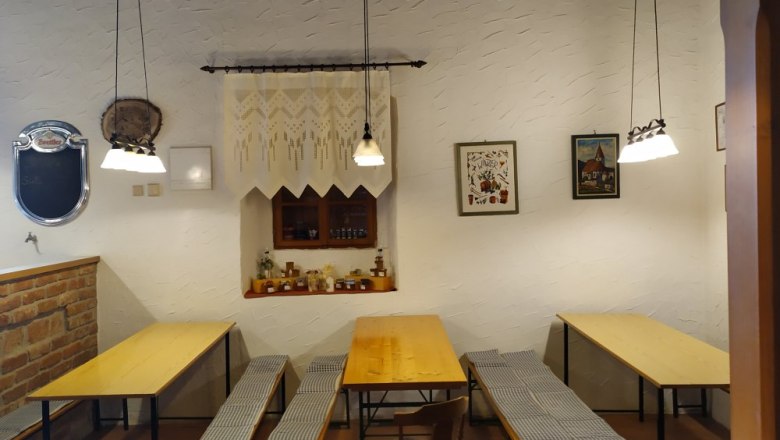 Gemütliche Stube mit Holztischen und Bänken, dekoriert mit Bildern und Lampen.