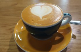 Eine Tasse Cappuccino mit Herz-Latte-Art auf einem Holztisch.