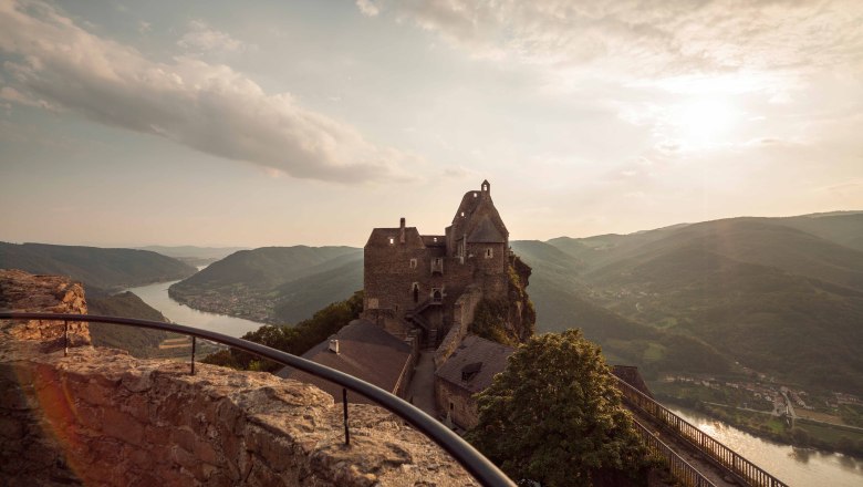 Burg Aggstein im Sommer mit Blick auf die Donau und umliegende Hügel.