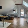Modern attic apartment with wooden floor, dining table, sofa and access to a balcony.