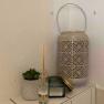 Decorative arrangement with scented sticks, candle, succulent and lantern on a white shelf.