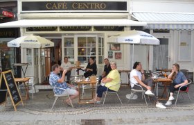 Menschen sitzen vor einem Café mit dem Namen Café Centro.