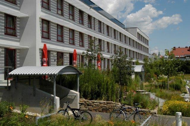 Kolping Campus Krems, LLC, © Kolping Campus Krems GmbH Modern building with several floors, surrounded by green landscape and bicycles in the foreground.