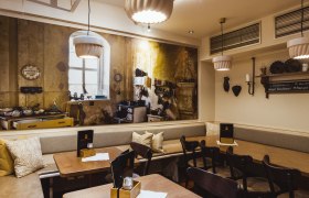 Gem&uuml;tliches Restaurant mit rustikalem Wandbild einer alten K&uuml;che.