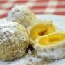 Three apricot dumplings on a plate, one of them sliced