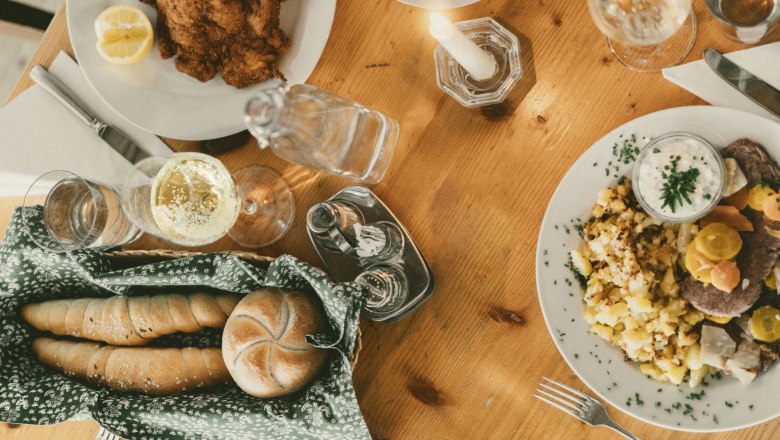 Table set with schnitzel, potato salad and drinks.