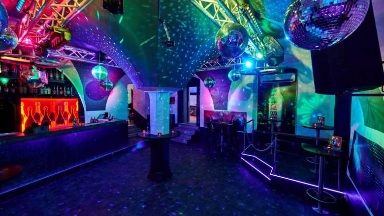 Innenansicht eines Clubs mit Discokugeln und bunter Beleuchtung.