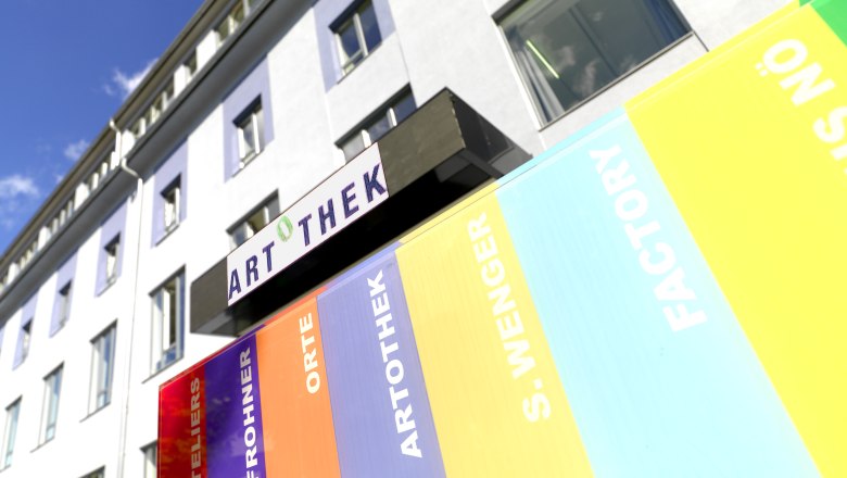 Exterior view of a building with Artothek sign and colorful stripes.