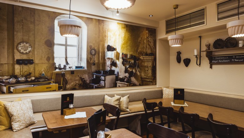 Gem&uuml;tliches Restaurant mit rustikalem Wandbild einer alten K&uuml;che.