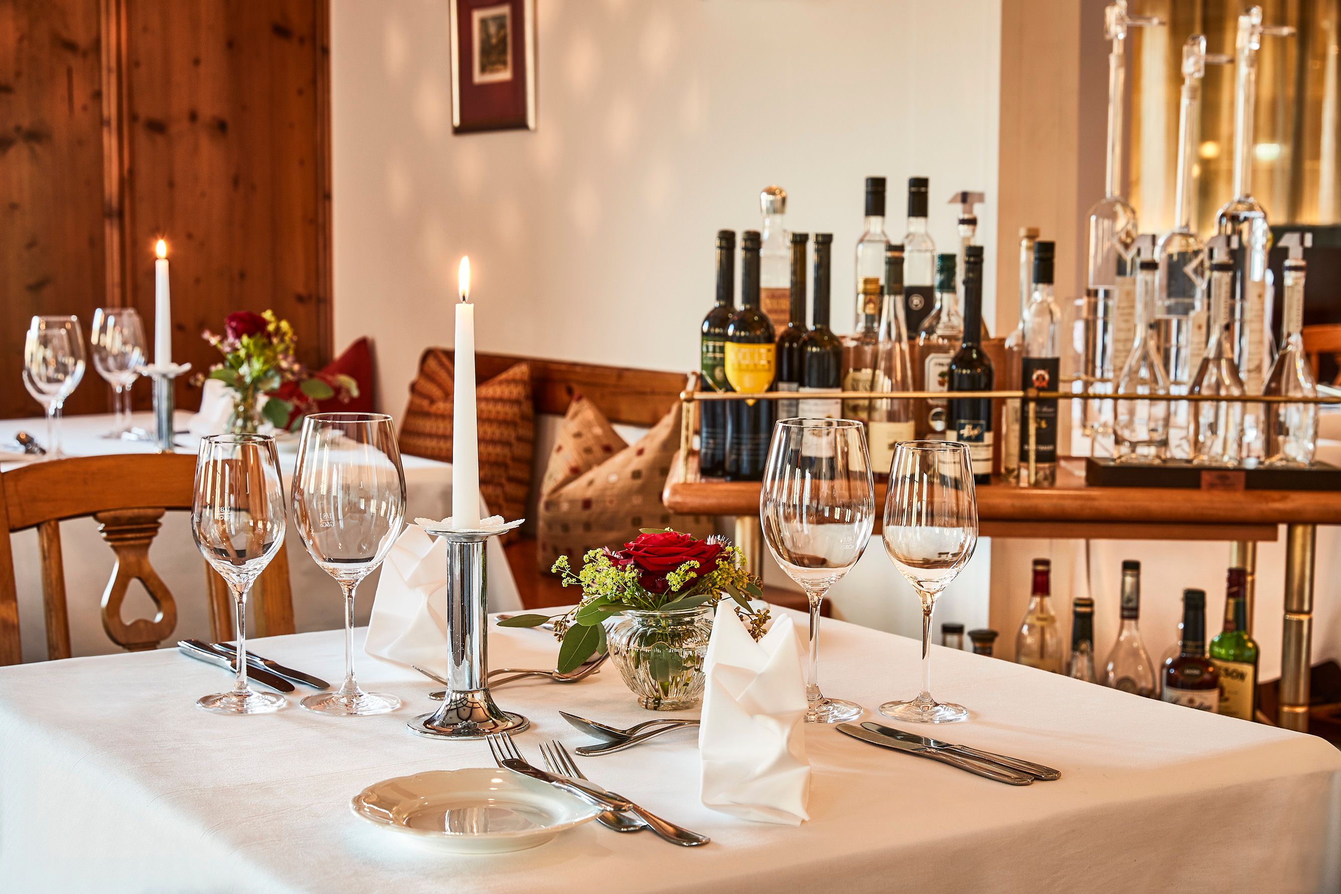 Eleganter Tisch in Hotel-Restaurant mit Weingläsern, Kerze und Blumen.