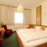 Comfortable hotel room with double bed, TV, flowers and curtains.