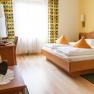 Comfortable hotel room with double bed, TV and curtains.